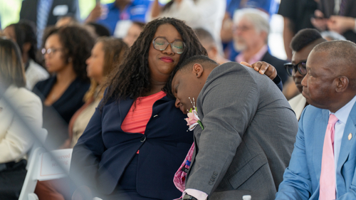 Family members of Candis Gabriella King sit together during the Queen Candis Act bill-signing ceremony at the Sentara Community Care Center in Newport News, Thursday, June 11, 2026. Candis's mother rests her head on another family member's shoulder as they listen to speakers, reflecting the emotional significance of the event honoring Candis's legacy.