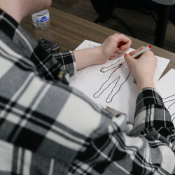 Close-up of a participant using markers to complete a body mapping exercise during a burn and trauma survivor support group session.