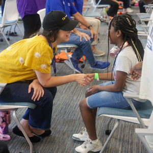 A Sentara volunteer sits in a chair directly across from a young girl and shakes her hand during the Shoes of Hope event at the ForKids Landmark Center in Chesapeake.