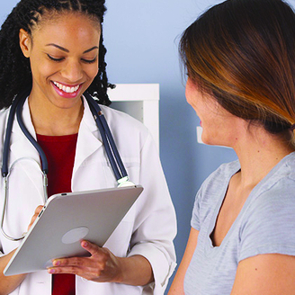 Healthcare professional reviewing information on a tablet during a patient consultation in a medical office setting.