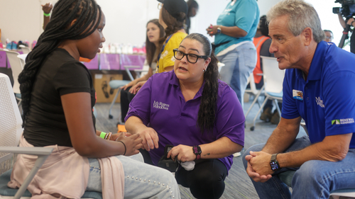 Two volunteers from Mr. Rogers Windows talk with a young girl during the Shoes of Hope event at the ForKids Landmark Center in Chesapeake. Volunteers connected one-on-one with children while helping them select and try on new shoes.
