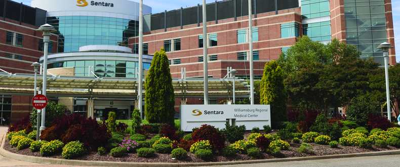 Exterior view of Sentara Williamsburg Regional Medical Center with flags and landscaped entrance.