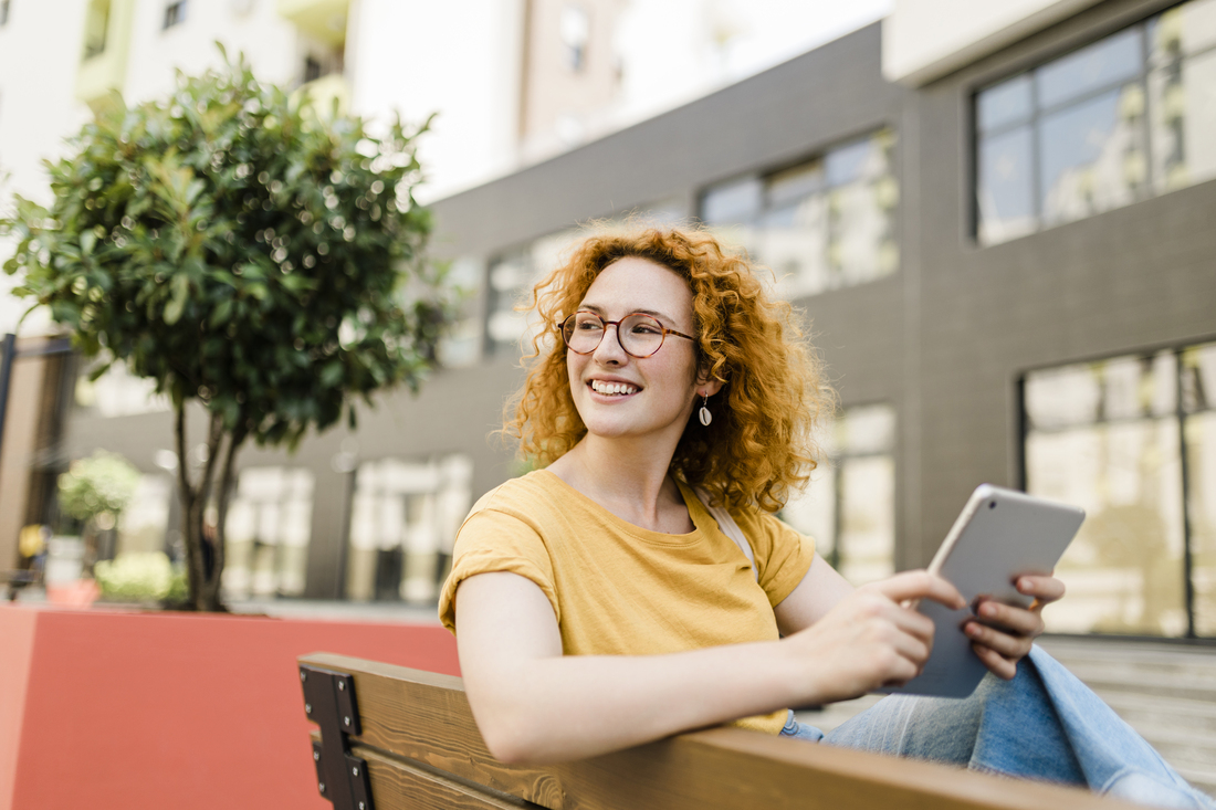 young woman with tablet on bench