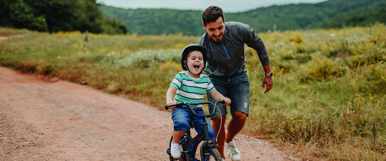 father teaching son to ride a bicycle