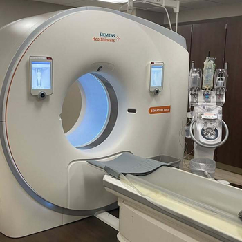 A Siemens Healthineers SOMATOM Force CT scanner in a clinical imaging suite, with a patient table extending from the gantry and a contrast injector positioned to the right.