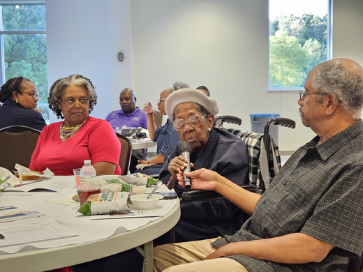 Leonora Jones, middle, shares her story with the room. Her son holds a microphone. Gail Bess is pictured far left.