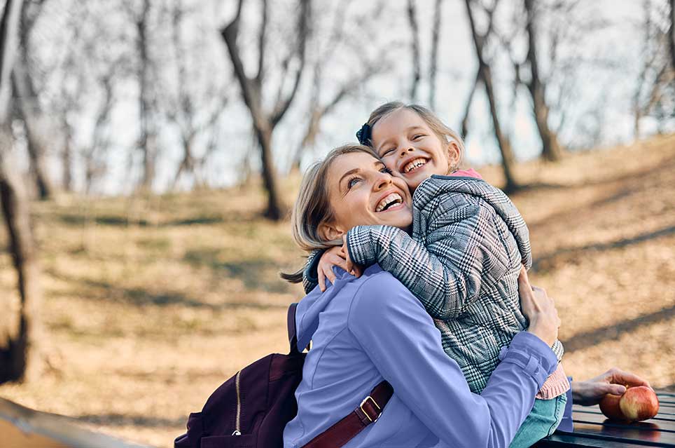 mother and daughter hugging, smiling and looking towards the sky
