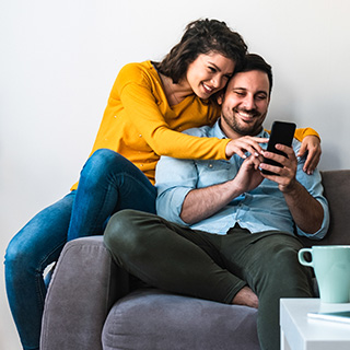 happy-couple-on-couch-looking-for-insurance-plans-on-phone.jpg