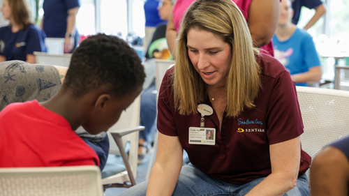 A Sentara Health volunteer helps a child with a new pair of shoes during the Shoes of Hope event in Chesapeake. Sentara colleagues joined community volunteers to personally assist children receiving new shoes and socks for the school year.