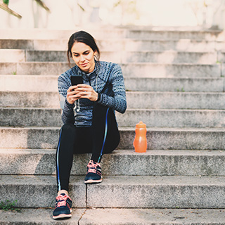 woman on steps looking at phone before working out
