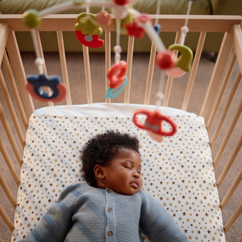 A baby sleeping safely in her crib