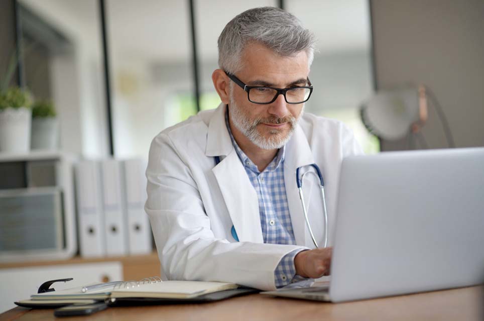 Doctor Working with Notepad and Computer