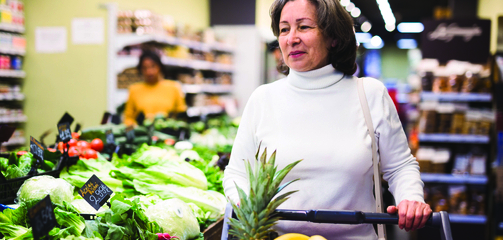 middle aged woman pushing shopping cart at the grocery store