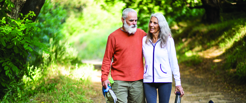 senior couple walking dog in woods