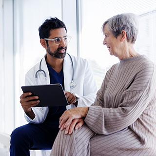 Doctor holding tablet talking with patient