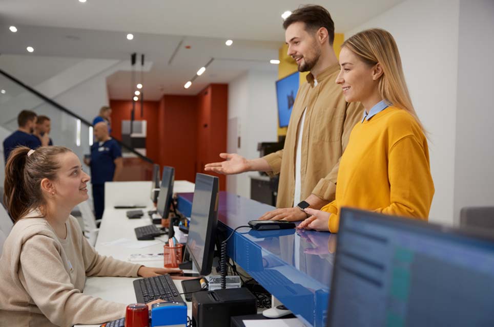 couple talking to medical staff at front desk