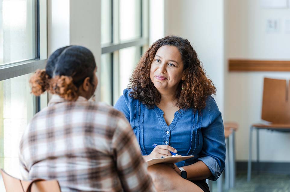 therapist with clipboard smiling at patient