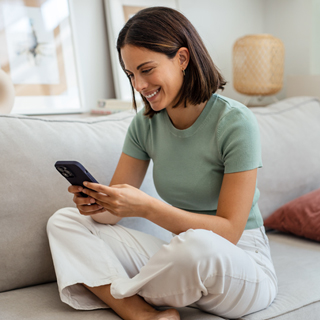 Young woman sitting on couch with mobile phone