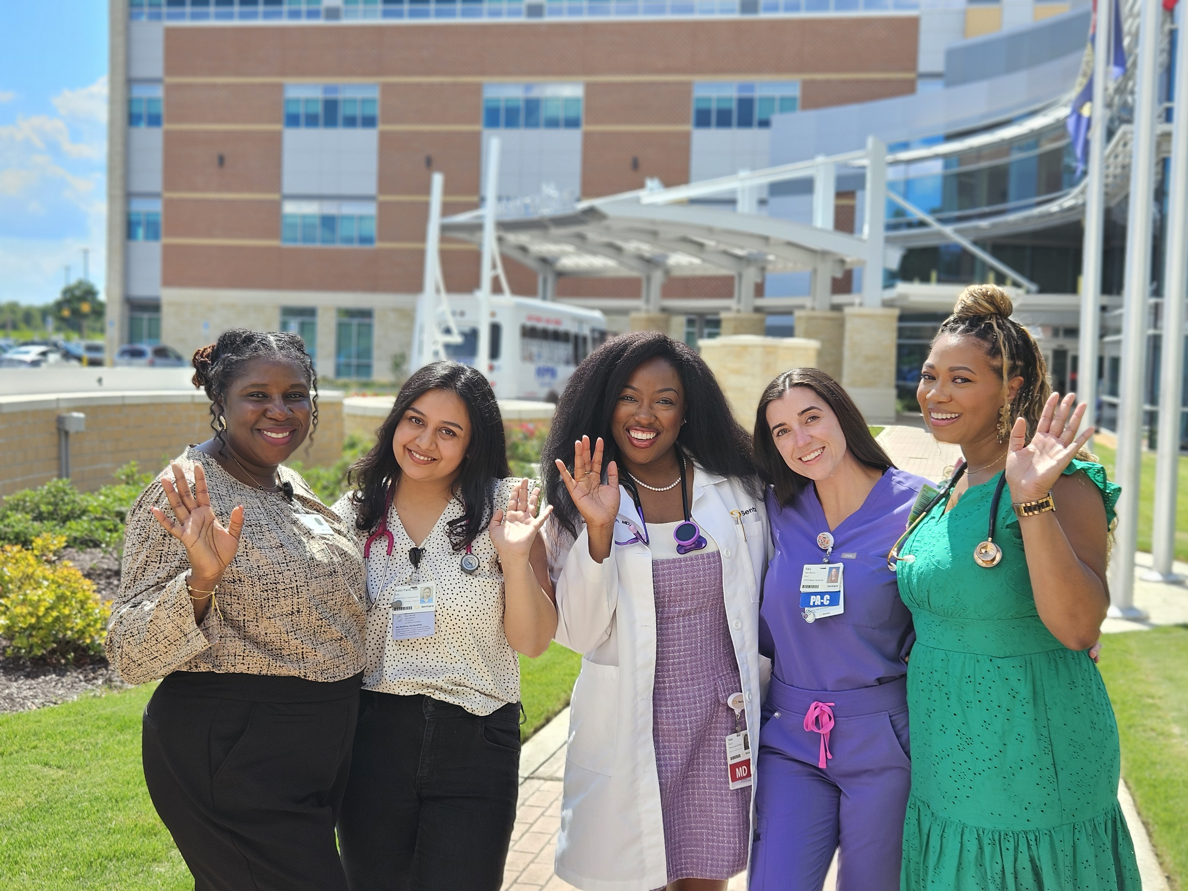 Five female providers stand and wave in front of Sentara Albemarle Medical Center.