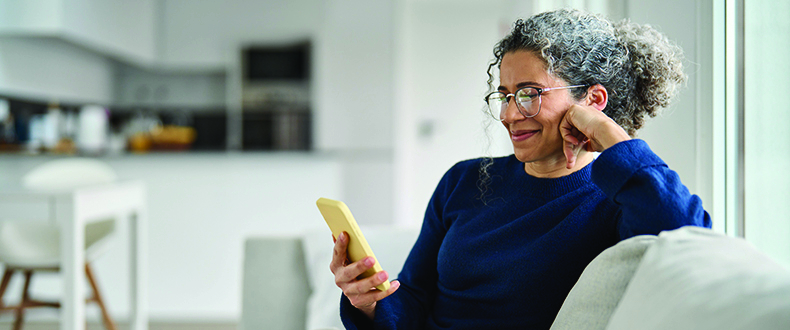 middle aged woman looking at her phone while sitting on the couch