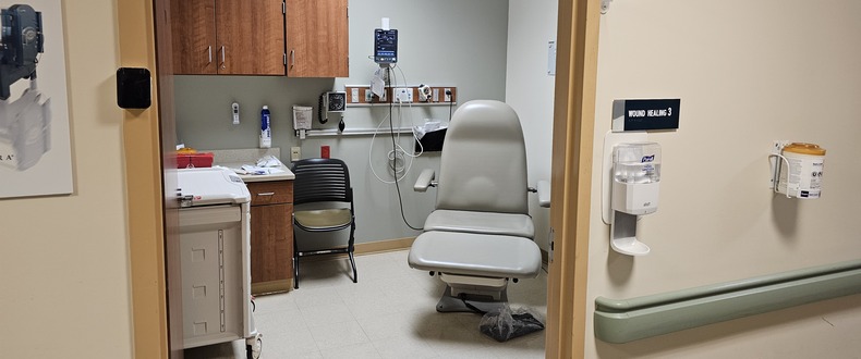 Wound healing exam room with treatment chair, medical equipment, and wall‑mounted monitors at a Sentara outpatient center.