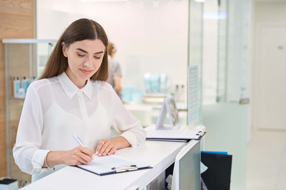 woman in clinical setting writing on clipboard