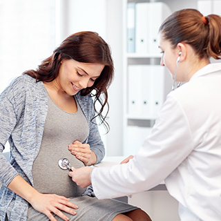 doctor holding stethoscope up to pregnant woman's stomach