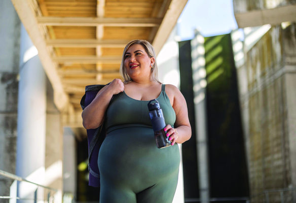 woman walking with yoga gear