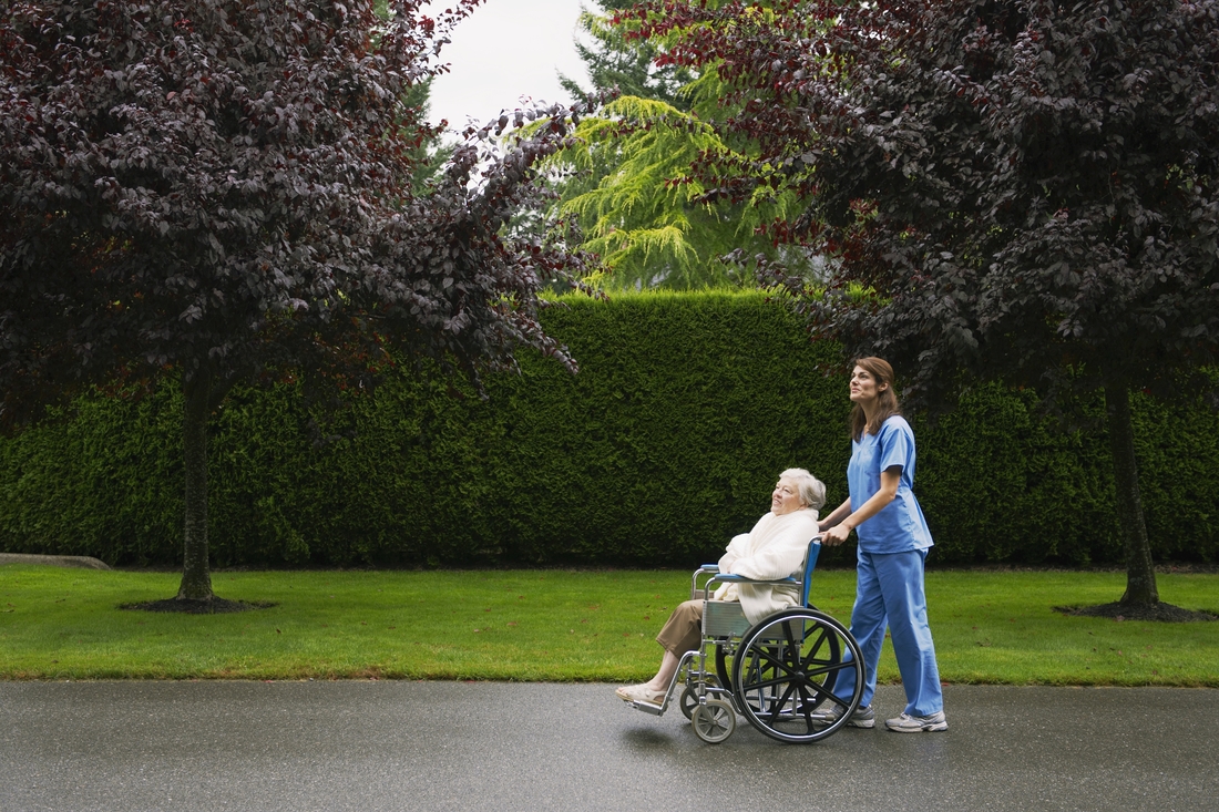 nurse pushing elderly woman in wheelchair