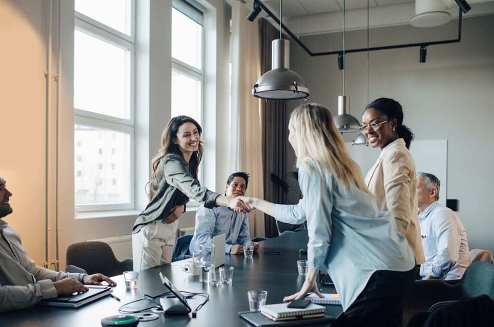 2 women shaking hands in meeting
