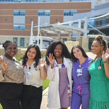 Five female providers stand and wave in front of Sentara Albemarle Medical Center.