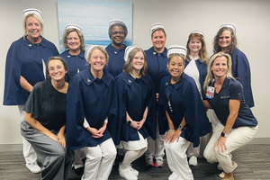 Members of Kathleen’s Angels, the nursing honor guard at Sentara Norfolk General Hospital, pose together, with most wearing traditional white nursing uniforms, caps and navy blue capes.