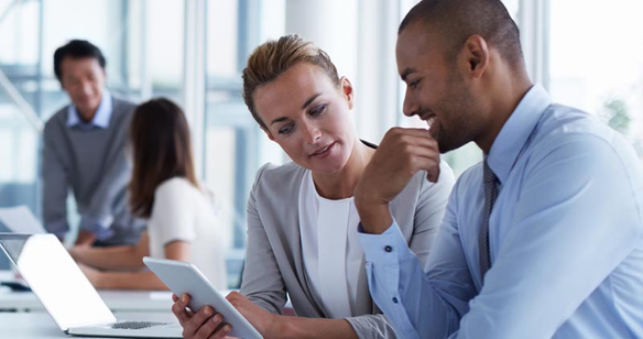 man and woman in business attire looking at a tablet