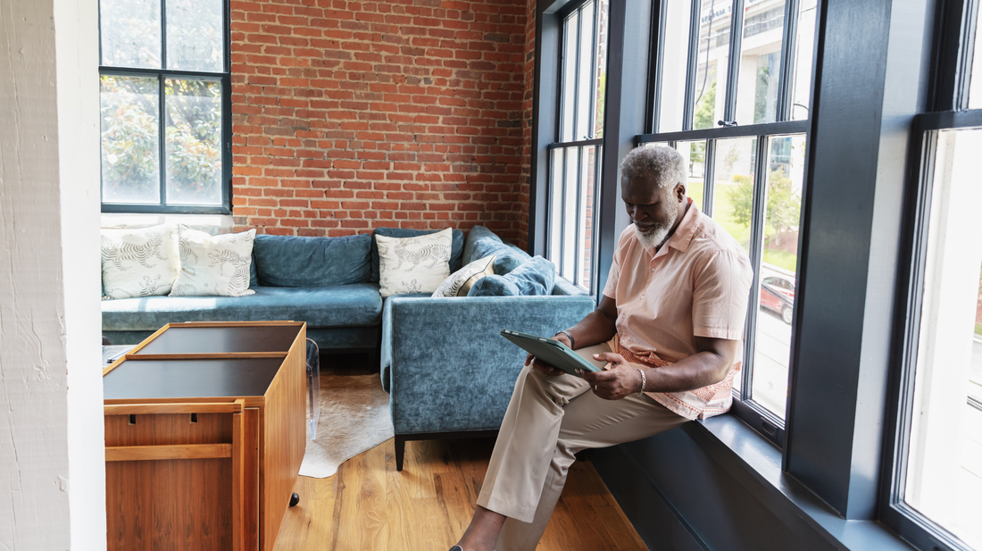 man sitting at window with tablet
