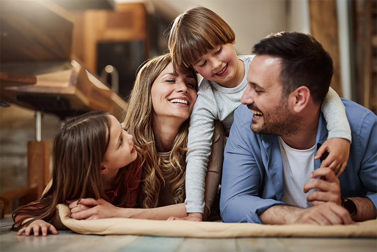 Family laying on floor smiling at each other