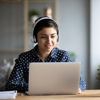 young woman sitting at a desk in front of a computer with headphones