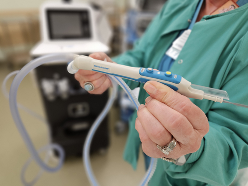 A Sentara operating room nurse holds a device that captures and filters surgical smoke before it can be breathed in by surgical teams.