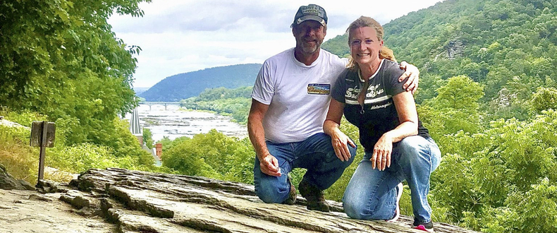  Sentara nurse and breast cancer survivor Andrea Helmbach and her husband, Eric, kneeling upon a rocky ledge overlooking Harper's Ferry, West Virginia.