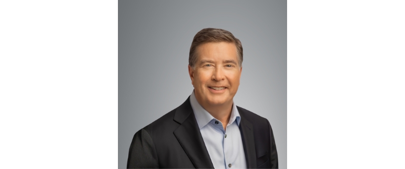 Professional studio headshot of Michael Cole, executive vice president and president of Sentara Health Plans, wearing a dark business jacket and light blue collared shirt against a gray background, facing the camera in a corporate portrait style.