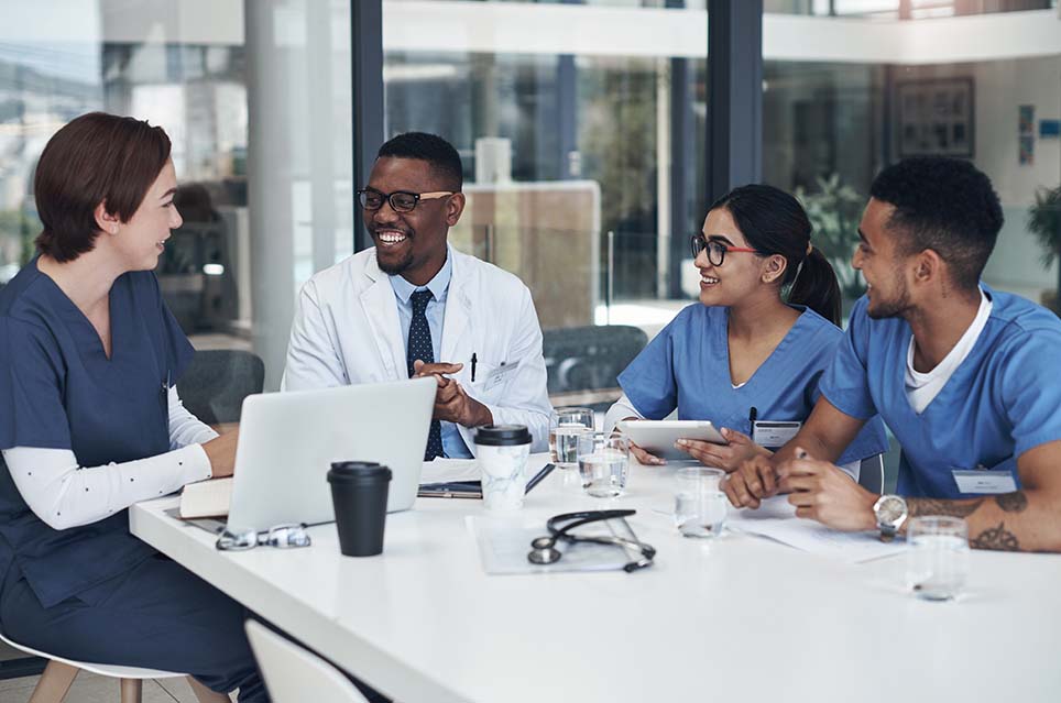 four smiling providers conversing around table