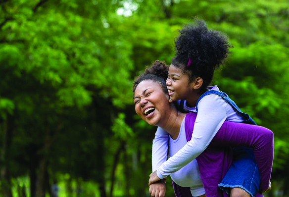 Individual carrying daughter on their back outside