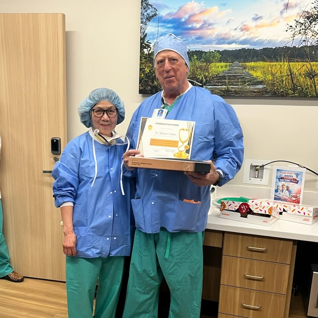 Surgical technologist stands next to a surgeon holding an award.